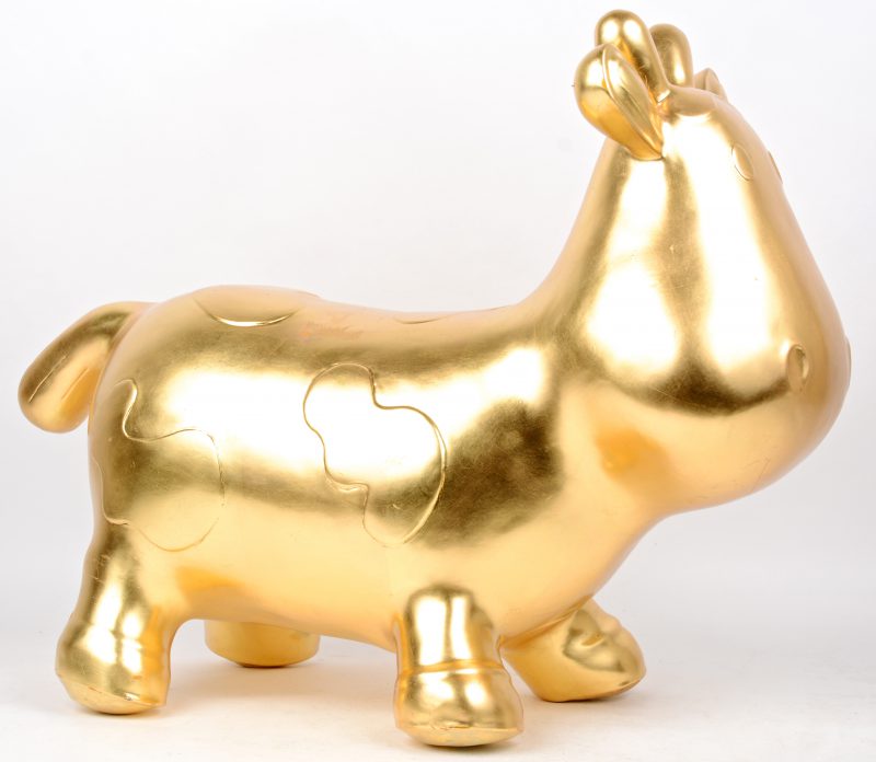 Een cartooneske koe van goudgepatineerd metaal.