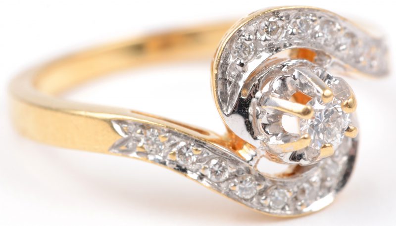 Een 18 karaats wit en geel gouden ring bezet met briljanten met een gezamenlijk gewicht van ± 0,20 ct.