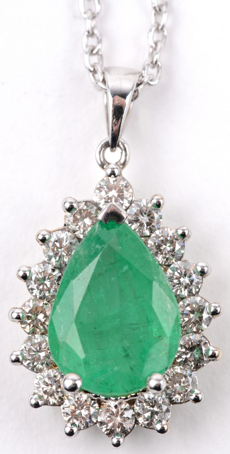 Een 18 karaats wit gouden ketting met hanger bezet met diamanten met een gezamenlijk gewicht van ± 0,80 ct. en een druppelvormige smaragd van ± 2,30 ct.