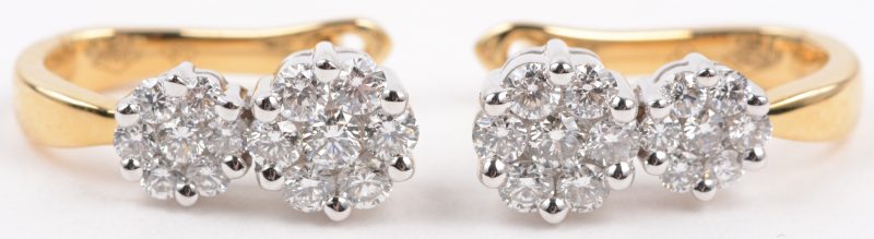 Een paar 18 karaats wit en geel gouden oorbellen bezet met diamanten met een gezamenlijk gewicht van ± 0,60 ct.