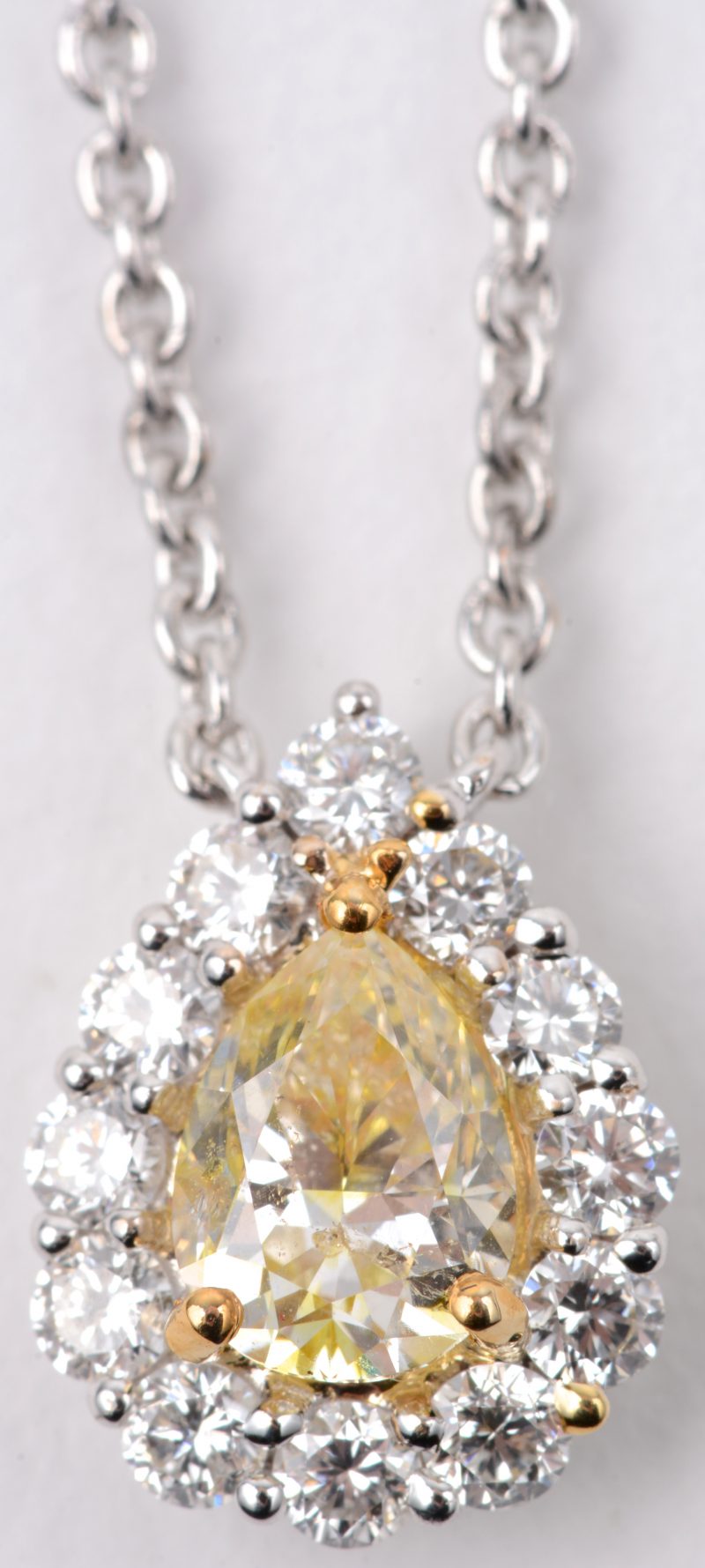 Een 18 karaats wit gouden ketting met briljanten en een druppelvormige hanger bezet met een fancy diamant van ± 0,65 ct. VVS1 en briljanten met een gezamenlijk gewicht van ± 0,52 ct.