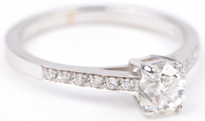 Een 18 karaats wit gouden ring met bezet een centrale diamant van ± 0,92 ct. VVS1 en briljanten met een gezamenlijk gewicht van ± 0,18 ct.