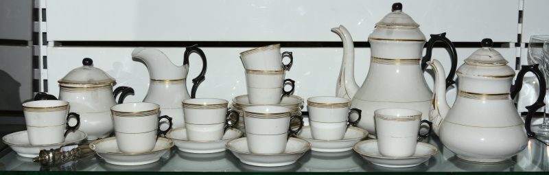 Een theeservies van wit, zwart en verguld porselein, bestaande uit een koffiepot, theepot, melkkannetje, suikerpot, acht kopjes en twaalf onderbordjes. We voegen er een zilveren suikertang aan toe.