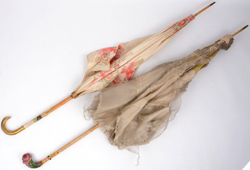 Twee antieke parasolletjes, waarvan één met borduursel en een polychroom houten handvat in de vorm van een roos en het andere met een geëmailleerd bloemendecor.