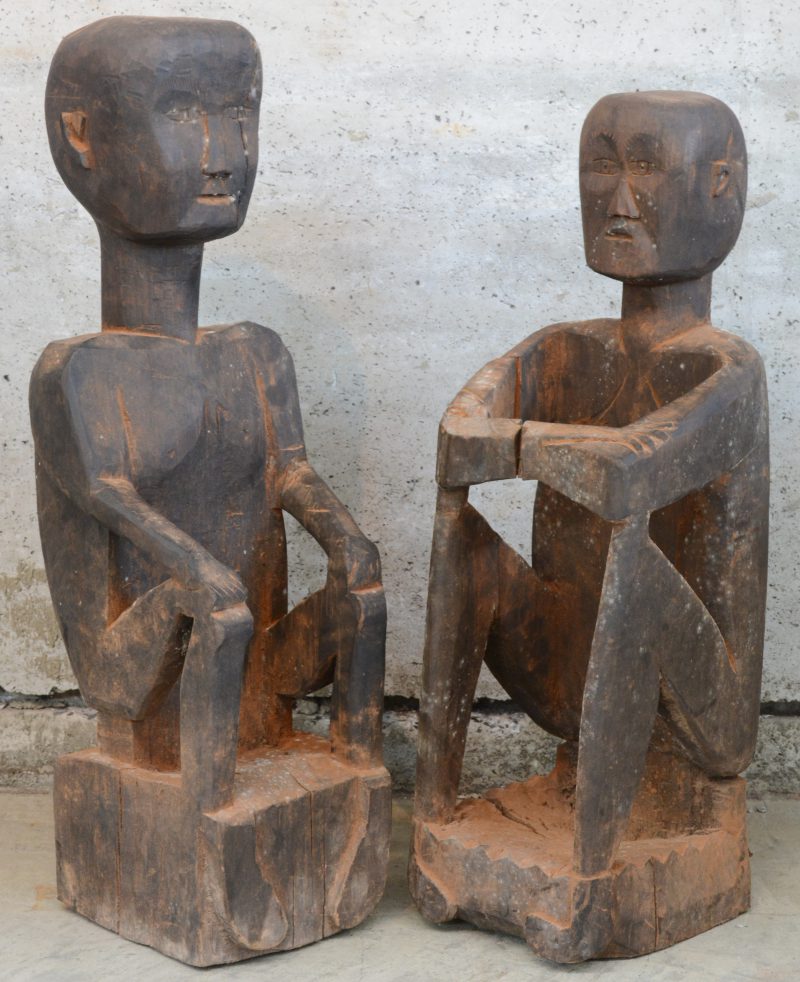 Twee zittende figuren van gebeeldhouwd hout. Laos. Enkele barsten.