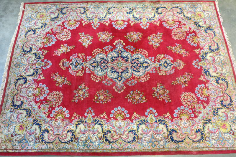 Een handgeknoopt Oosters wollen tapijt, gedecoreerd met bloemenmotieven.