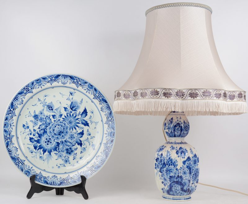 Grote schotel van blauw en wit aardewerk met bloemendecor. Achteraan gemerkt: Delft Royal Gouda Holland en genummerd 2965/40. Evenals een kalebasvormige vaas met blauw en wit decor, gemonteerd als lamp, onderaan gemerkt: Deflt.