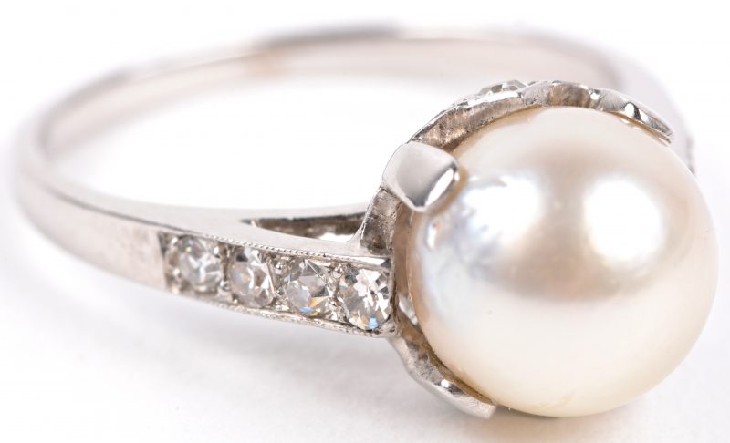 Een 18 karaats wit gouden ring bezet met briljanten met een gezamenlijk gewicht van ± 0,20 ct. en een parel.