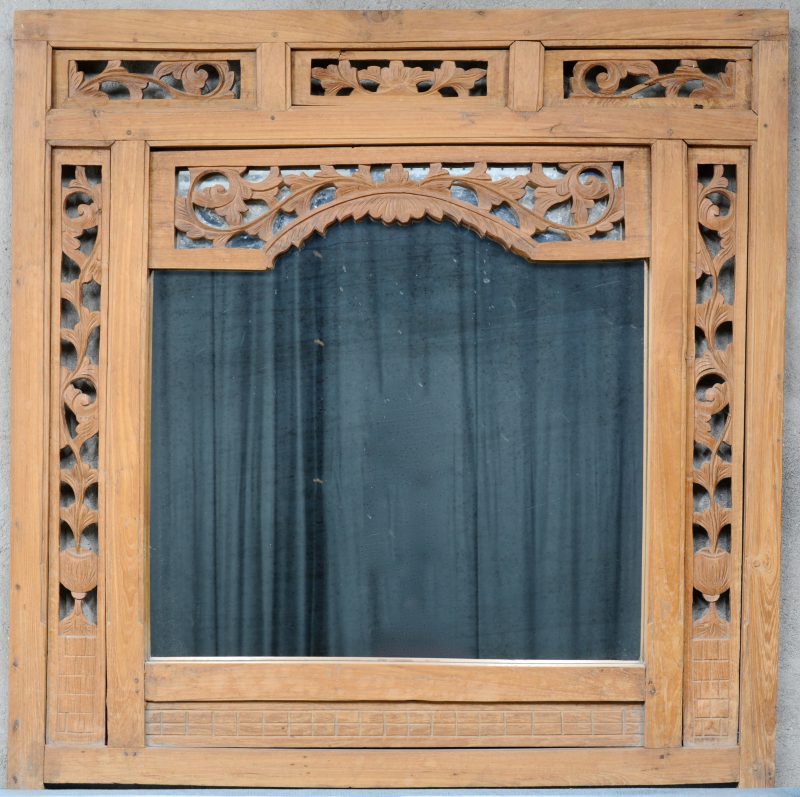Een spiegel in gebeelmdhouwde en opengewerkte houten lijst.