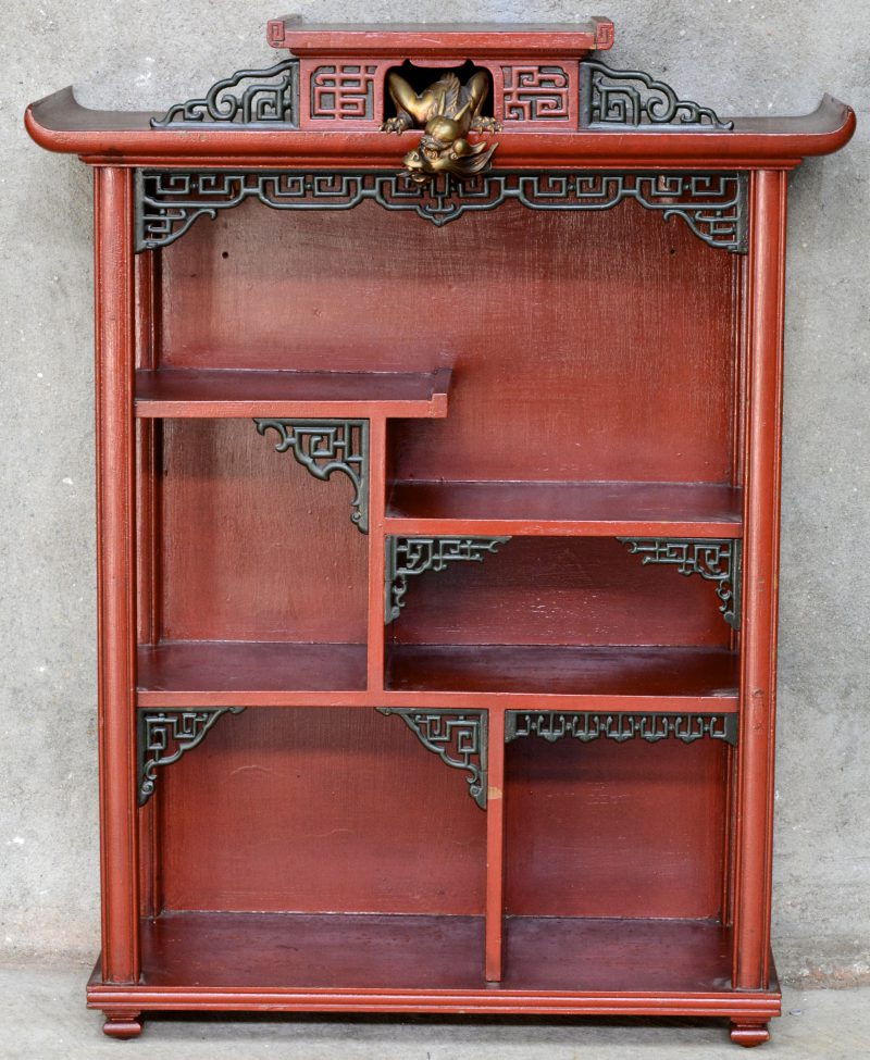 Een Chinees wandrekje van rood en groen gelakt hout in ongelijke niveaus en bovenaan getooid met een bronzen drakenkopje. Eind XIXe eeuw.