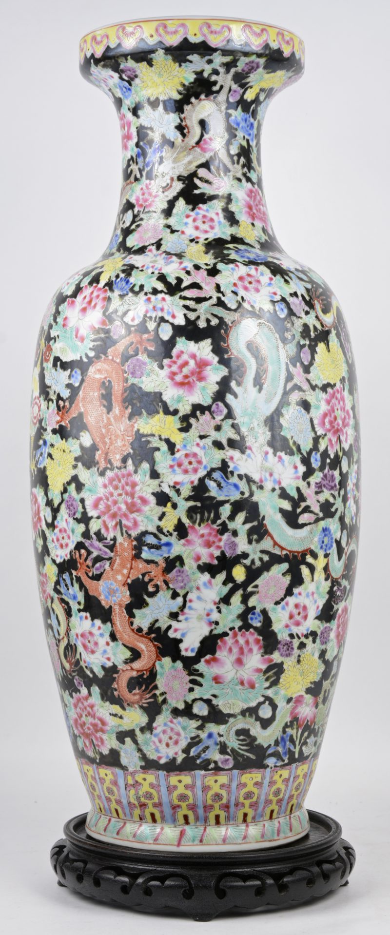 Een vaas van meerkleurig Chinees porselein met een famille-noiredecor van bloemen en draken. Onderaan gemerkt. Op houten sokkeltje.