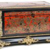 Een kistje van zwartgelakt hout, versierd met boullemarquetterie van messing en schildpad en met bronsbeslag. Binnenin twee porseleinen flesjes en een dekseldoosje met meerkleurige en vergulde decors. XIXe eeuw.