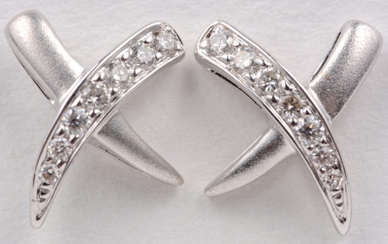 Een paar 18 karaats wit gouden oorbellen bezet met diamanten met een gezamenlijk gewicht van ± 0,18 ct.