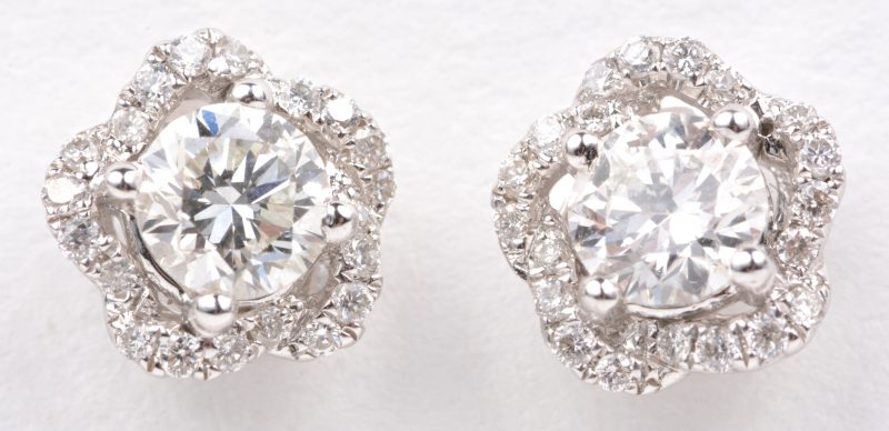 Een paar 18 karaats wit gouden oorbellen bezet met twee centrale  diamanten met een gezamenlijk gewicht van ± 0,60 ct. en briljanten met een gezamenlijk gewicht van ± 0,18 ct.