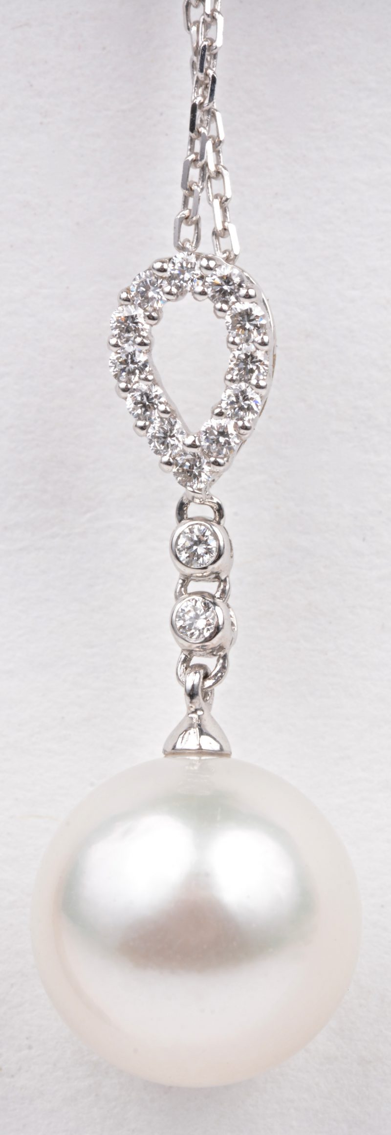 Een 18 karaats wit gouden ketting met hanger bezet met diamanten met een gezamenlijk gewicht van ± 0,18 ct. en een Australische parel van 12 mm. Met certificaat.