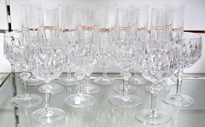 Een reeks glazen van geslepen kleurloos kristal, bestaande uit negen champagnefluiten en zes wijnglazen. Onderaan gemerkt. Eén fluit met schilfer.