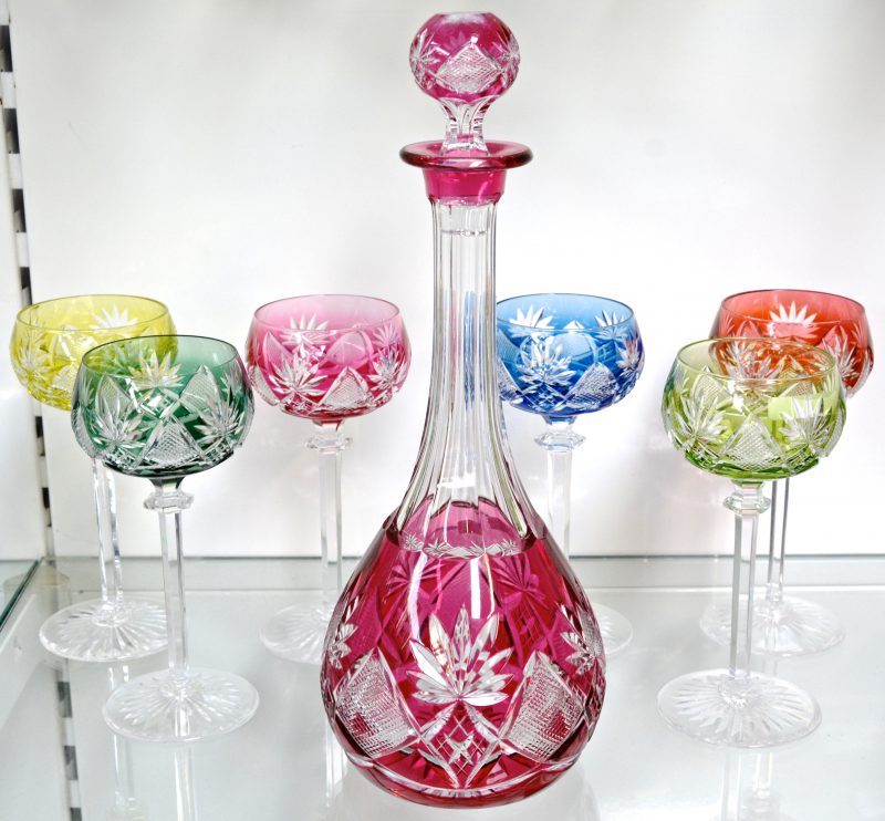 Een lot van zes glazen van geslepen kristal in verschillende kleuren. Met bijpassende karaf. Jaren ‘30. Niet gemerkt. Enkele kleine schilfers.
