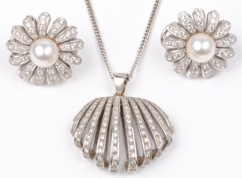 Een 18 karaats wit gouden ketting met schelpvormige hanger en bijpassende oorbellen bezet met diamanten met een gezamenlijk gewicht van ± 3 ct. en twee parels.
