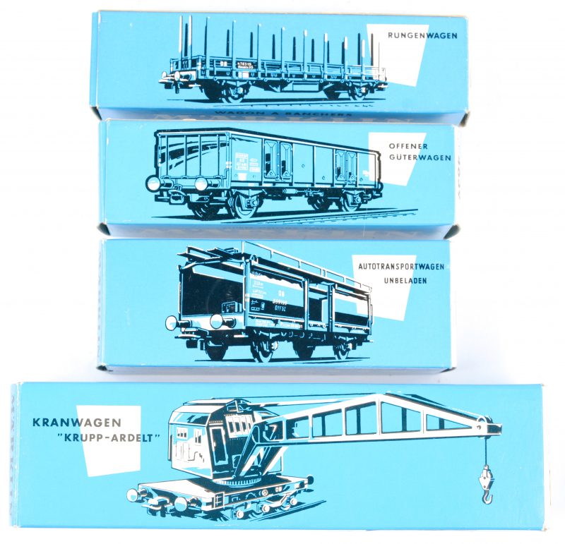 Vier goederenwagons voor spoortype Ho in originele doosjes: - Open wagon met steunpalen.- Spoorkraan ‘Krupp-Adelt’.- Lege autotransportwagon.- Open goederenwagon.