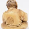 Een antieke Japanse netsuke van gesculpteerd ivoor ion de vorm van een zittende man. Onderaan gesigneerd.