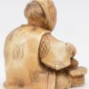 Een antieke Japanse netsuke van gesculpteerd ivoor ion de vorm van een zittende man die een vis ontschubt. Onderaan gesigneerd.