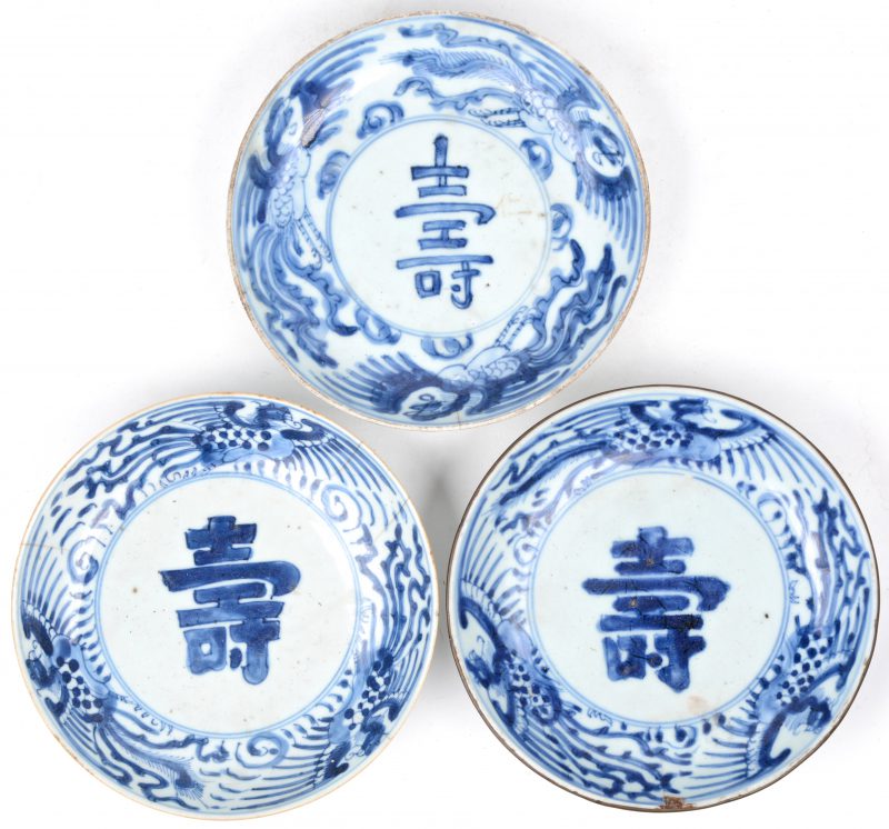 Drie schoteltjes van Chinees porselein met een blauw op wit decor. Haarscheuren en schilfers.