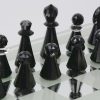 Een schaakspel uit de reeks “Silver Crystal” met zwarte en kleurloze stukken op een spiegelend speelbord en in originele doos. Zwarte koning gelijmd.
