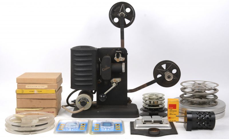 Een oude projector met een groot deel accesoires en films.