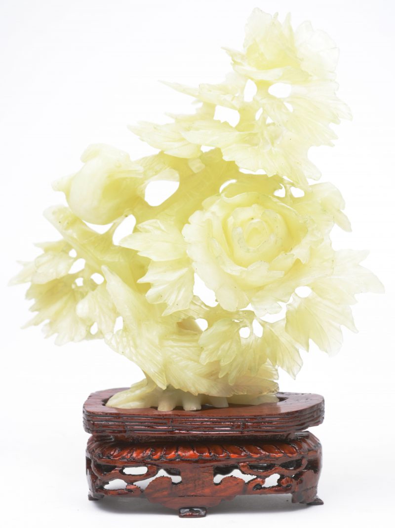 Een bloemenstruik met vogel van gesculpteerd jade. Op houten sokkeltje.