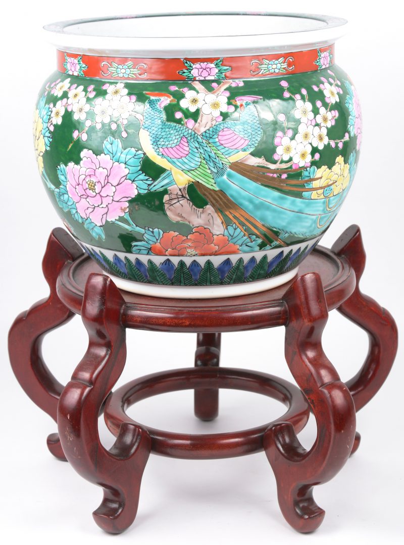 Een Japanse cache-pot van meerkleurig porselein, versierd met een bloemendecor op groene fond. Met houten sokkel.