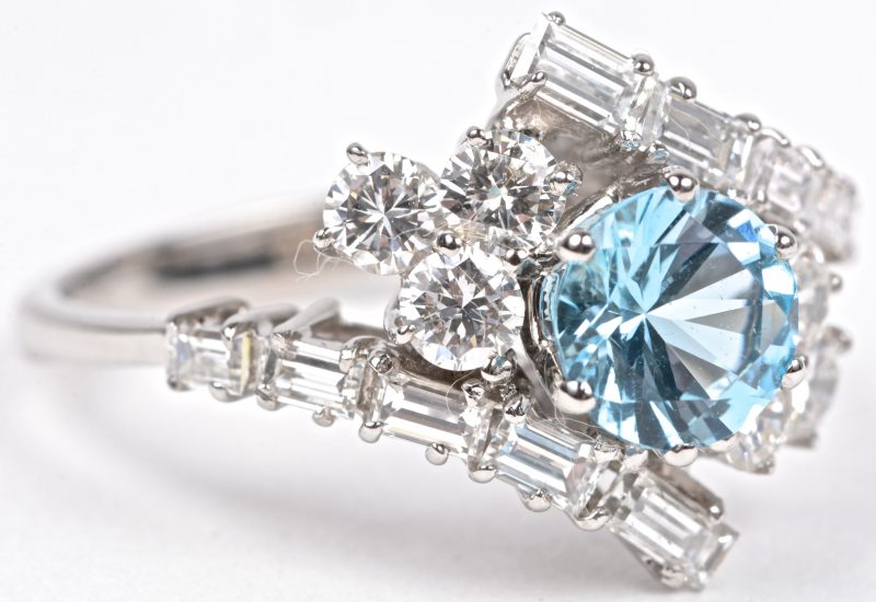 Een 18 karaats wit gouden ring bezet diamanten en baguettes met een gezamenlijk gewicht van ± 1 ct. en een London blue topaas van ± 1,25 ct.