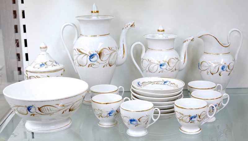 Een Louis-Philippe koffie- en theeservies van Brussels aardewerk met blauw en verguld bloemendecor, bestaande uit een theepot, een theepot, een melkkan, suikerpot met deksel en koekjesschaal, zeven ondertassen en zes kopjes. Gaaf. Medio XIXe eeuw