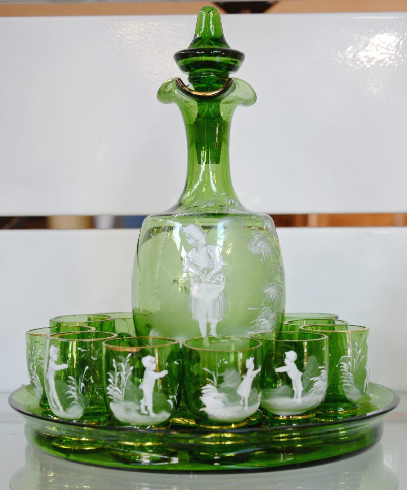 Een karafje van groen glas met twaalf glaasjes op dienblaadje.