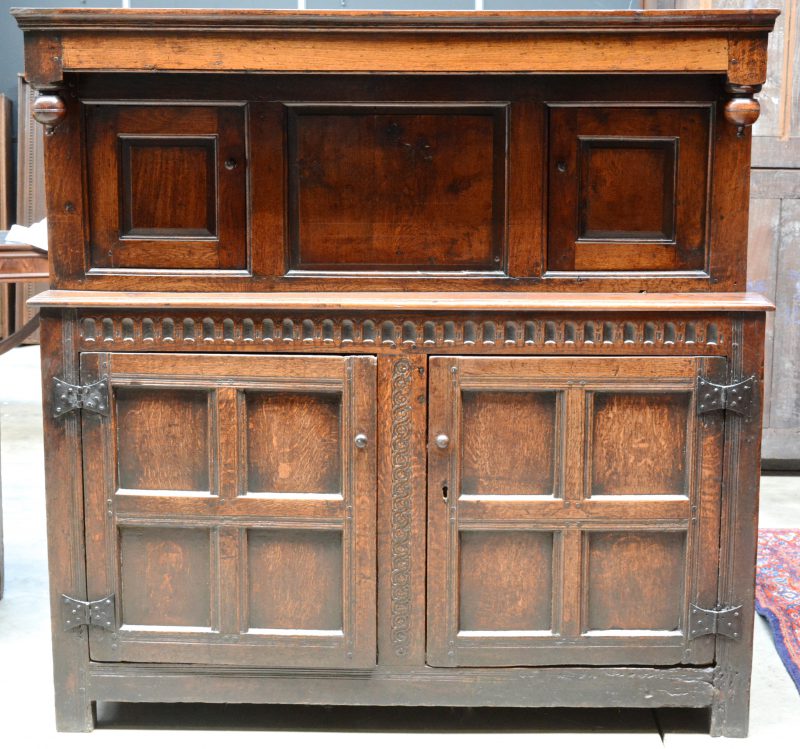 Een in twee delen opgebouwd eikenhouten meubel, met bovenaan twee kleine paneeldeuren en onderaan twee grote deuren en versierd gebeeldhouwde motieven. Van oorsprong XVIIe eeuw.