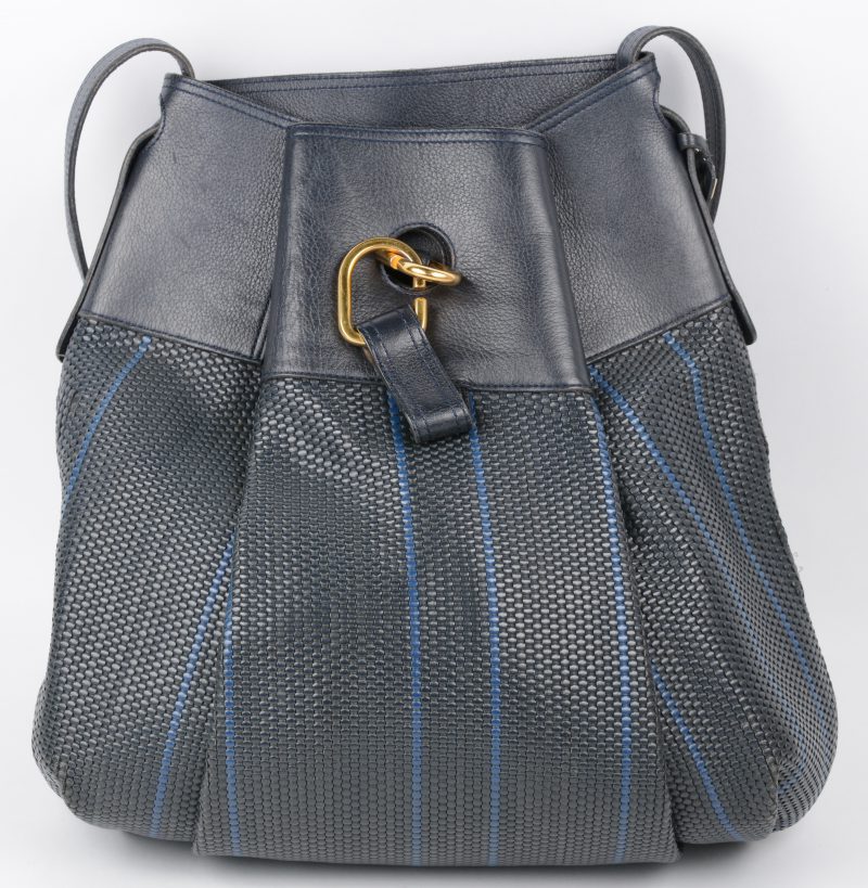 Een blauwe en met lichtblauwe streepjes geweven lederen handtas. Met stofzak.