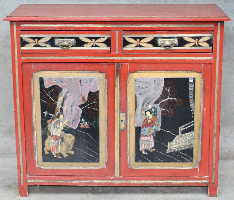 Een roodgelakt buffetkastje met twee laden en twee deuren, versierd met Chinese decors.