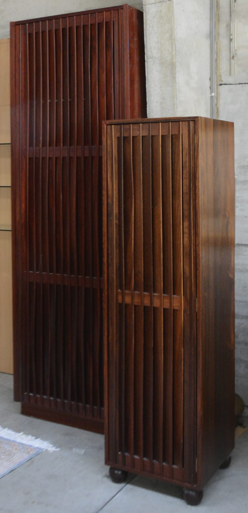 Een lot van twee kleerkasten uit palissanderhout. Periode 1990. Een inbouwkast met twee legplanken en een gechromeerde stang en een vrijstaande kast op bolpoten voorzien van drie legplanken. Lacune aan inbouwkast.