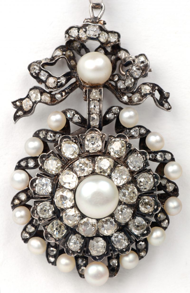 Een 18 karaats wit gouden gerodeerde broche bezet met diamanten oude slijp in zilver gezet met een gezamenlijk gewicht van ± 5 ct. en parels. 0mstreeks 1880.