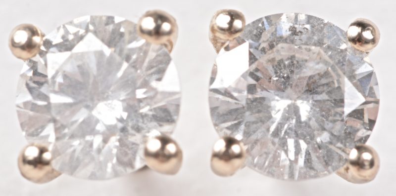 Een paar 18 karaats geel gouden oorbellen bezet met twee diamanten met een gezamenlijk gewicht van ± 0,50 ct.