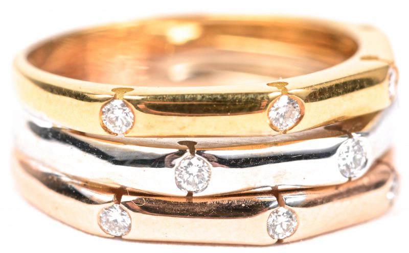 Een 18 karaats drie kleuren gouden ring bezet met briljanten met een gezamenlijk gewicht van ± 0,29 ct.