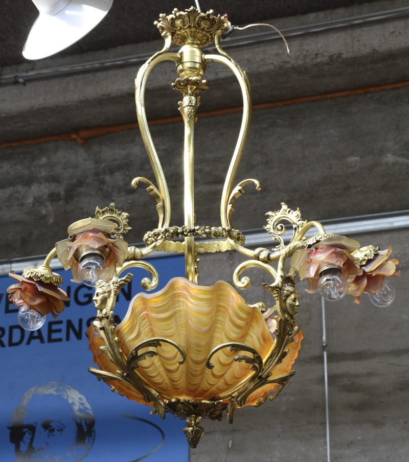 Een verguld bronzen luchter met drie dubbele lichtpunten met bloemvormige kapjes en centrale schelpvormige coupe van gesatineerd glas. XIXe eeuw.