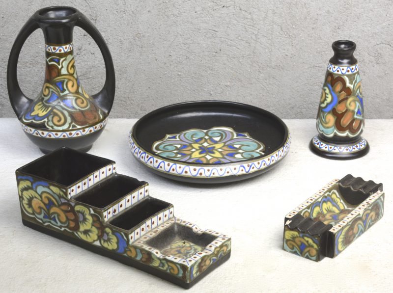 Een lot meerkleurig aardewerk in de stijl van Gouda, bestaande uit twee vazen, een diepe schotel, een asbak en een asbak met drie vakken in trapvorm. Onderaan gemerkt. Asbak met schilferschade.