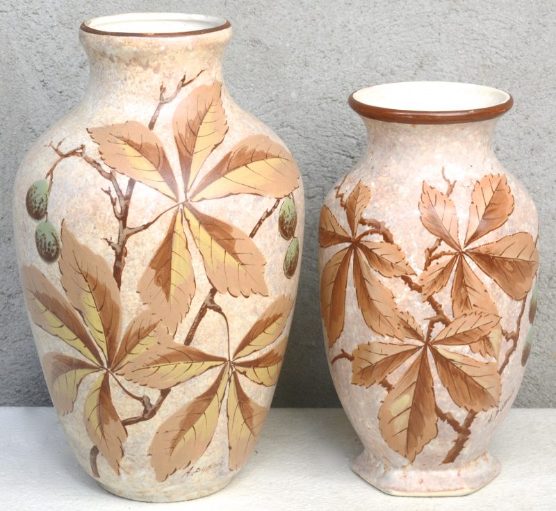 Twee vazen van meerkleurig aardewerk met een decor van kastanjebladeren. Gesigneerd ‘A. Dubois’. Onderaan gemerkt.