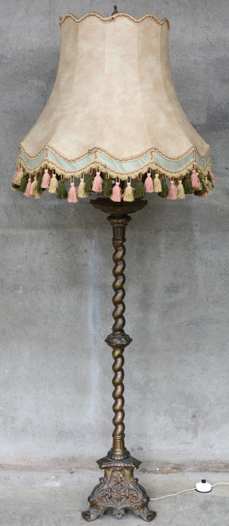 Een staande lamp van koper in barokke stijl.