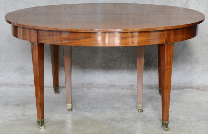 Een verlengbare ovale tafel van mahoniehout met zes tapse poten. Met twee verlengbladen.