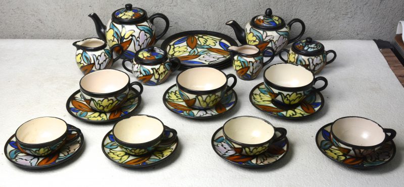 Twee driedelige theestellen van meerkleurig aardewerk in de stijl van Gouda, waarbij één met drie kopjes en drie borden en één met vier kopjes.