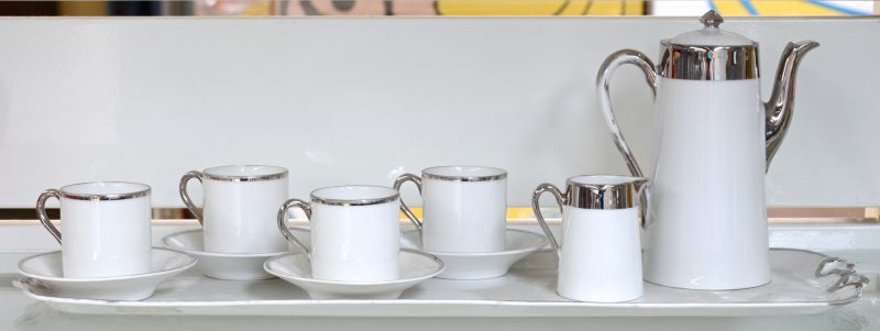 Een porseleinen theesetje voor vier personen met verzilverde randen. Op dienblad.