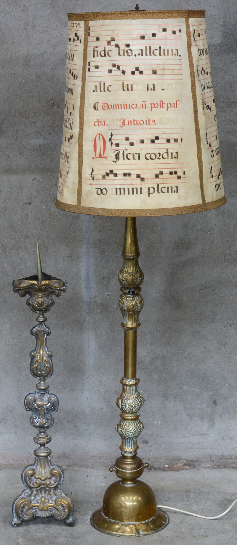 Twee verschillende messingen kandelaars, waarbij één barokke en één gemonteerd als staande lamp.