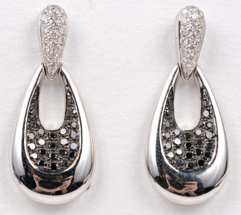 Een paar 18 karaats wit gouden oorbellen bezet met witte en zwarte diamanten met een gezamenlijk gewicht van ± 0,52 ct.