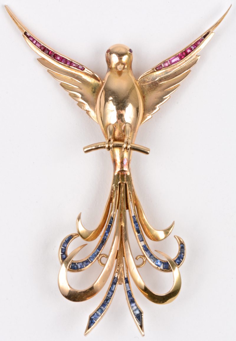 Een 14 karaats geel gouden broche in de vorm van een vogel bezet met robijnen en saffieren met een gezamenlijk gewicht ± 1 ct. (één saffiertje ontbreekt).